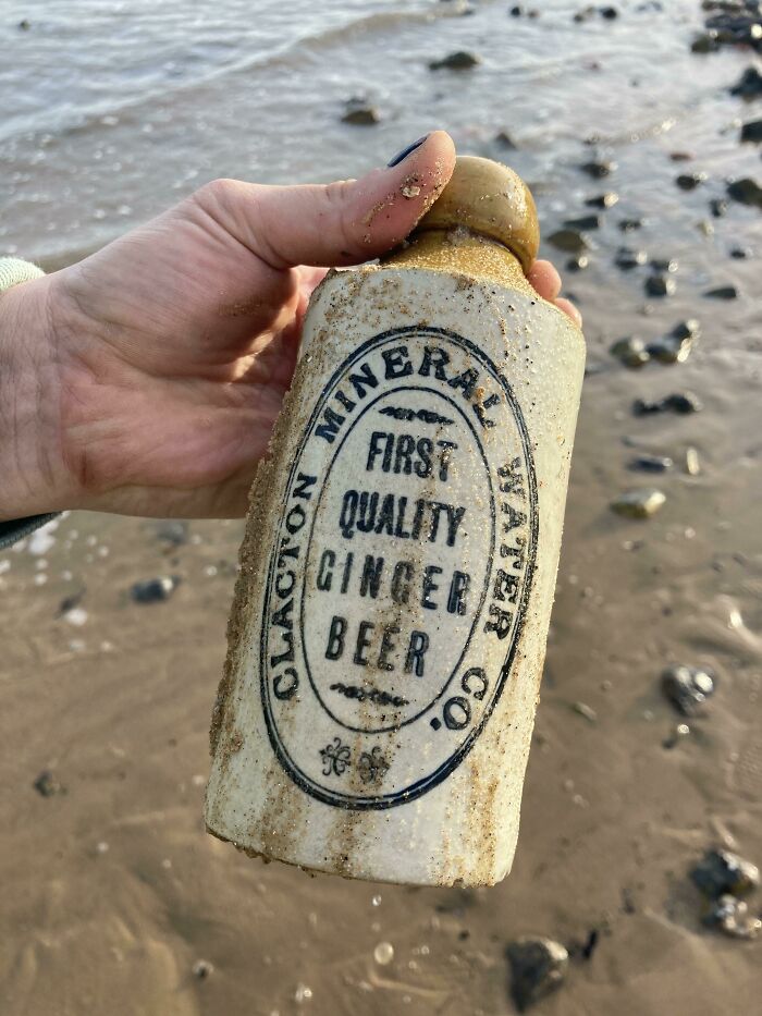 Hand holding a vintage ginger beer bottle found washed ashore, marked "Claxton Mineral Water Co."