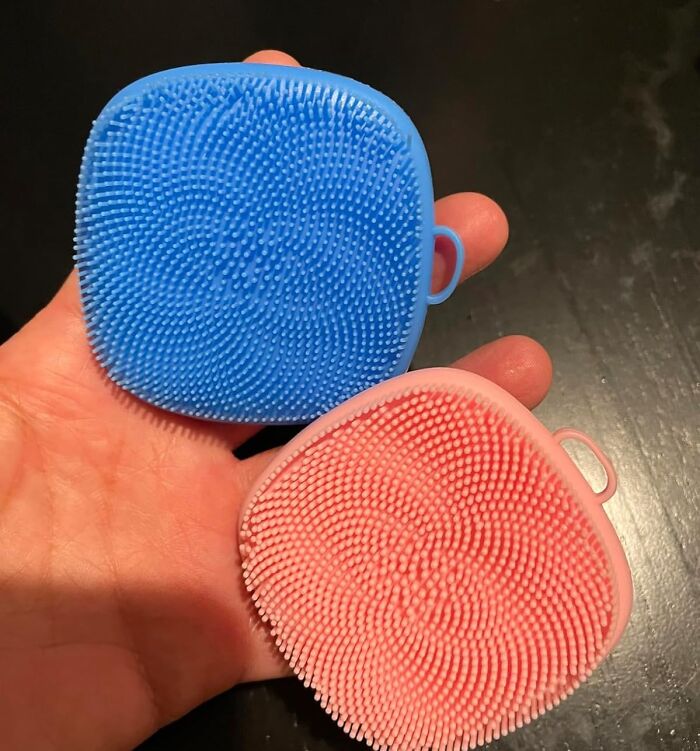 Hand holding two silicone scrubbers in blue and red, popular most-wished-for Amazon finds for home cleaning.