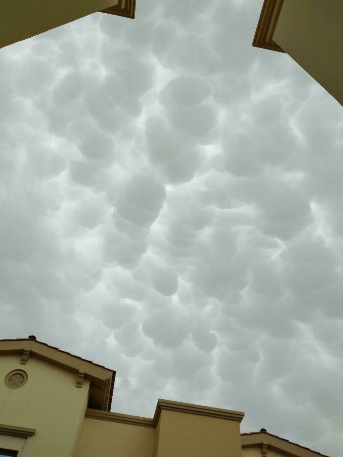 Fascinating cloud shapes above rooftops, with unique patterns that seem surreal.