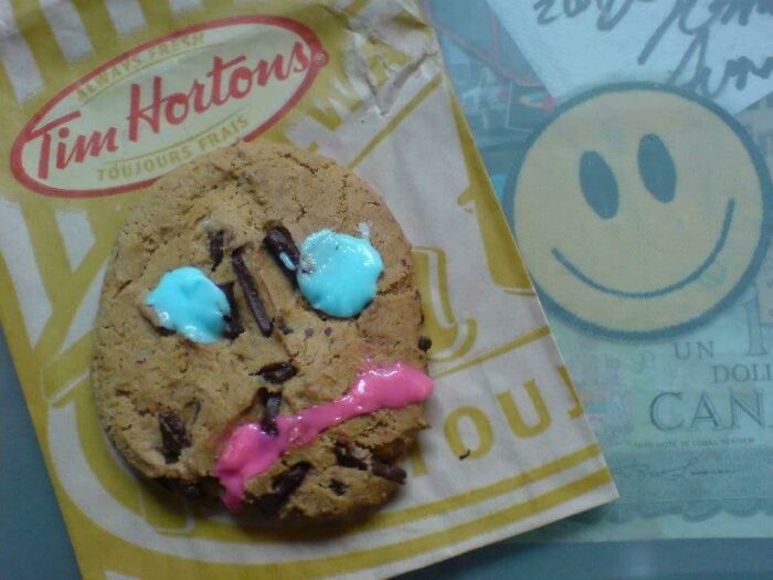 A cookie from Tim Hortons with a messy face design, symbolizing regret in spending money.