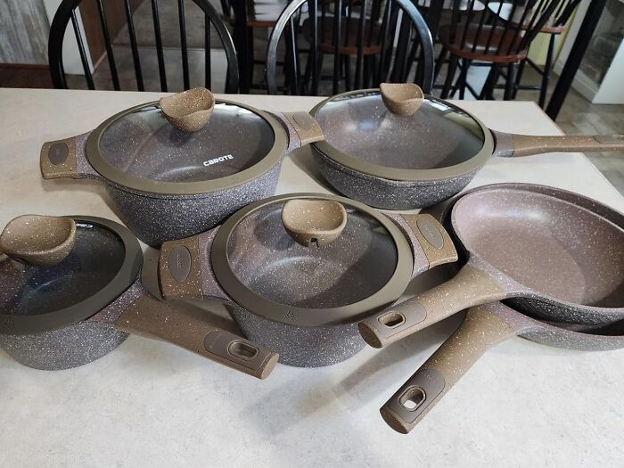 Set of non-stick cookware with lids, one of the most-wished-for Amazon finds, displayed on a kitchen table.