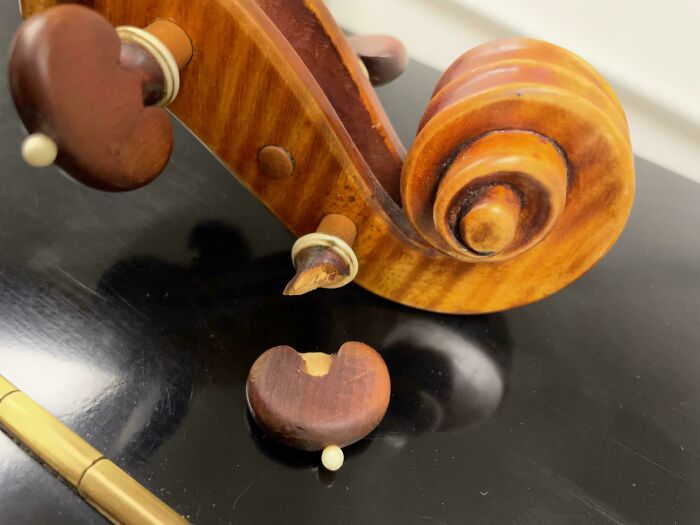 Broken violin scroll on a black surface, illustrating instant regret in spending money.