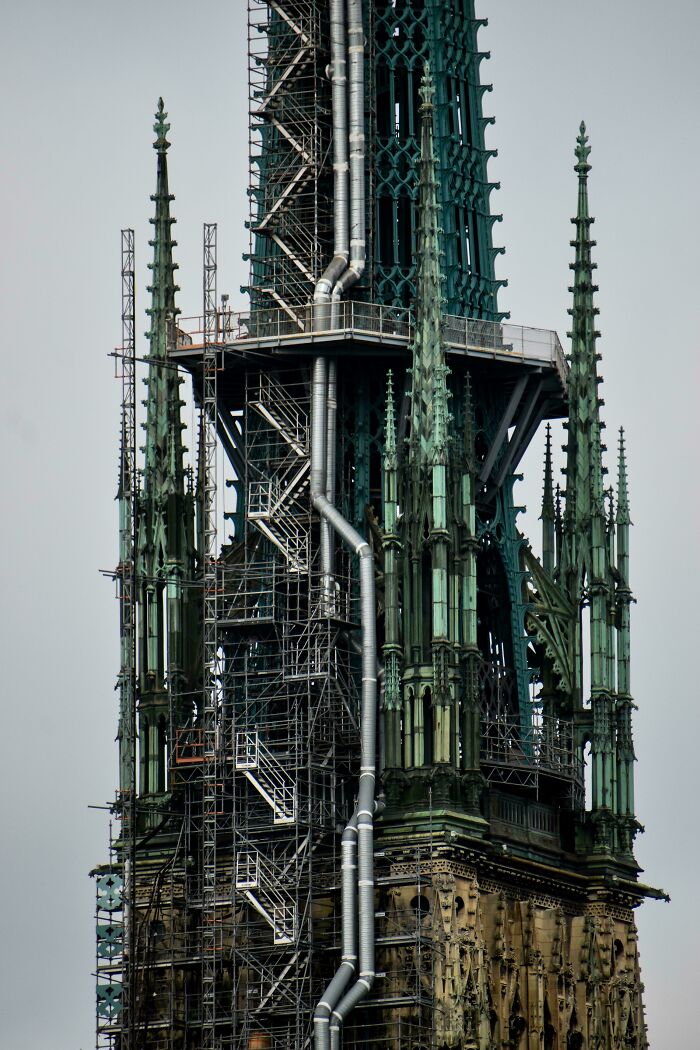 Gothic building under renovation with scaffolding and pipes, exuding an evil aura like a supervillain headquarters.