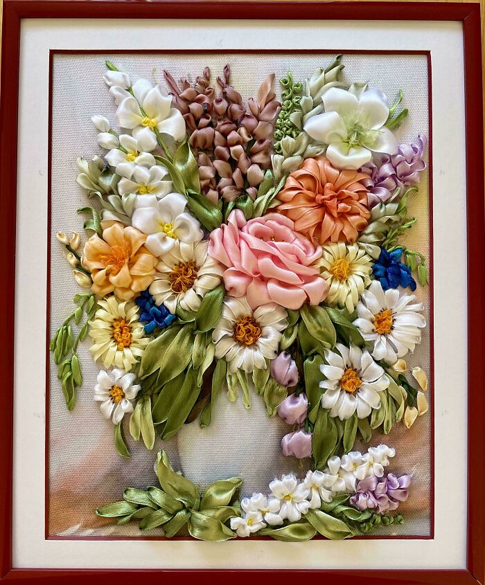 Vibrant floral embroidery design featuring various colorful flowers and green leaves in a framed art piece.