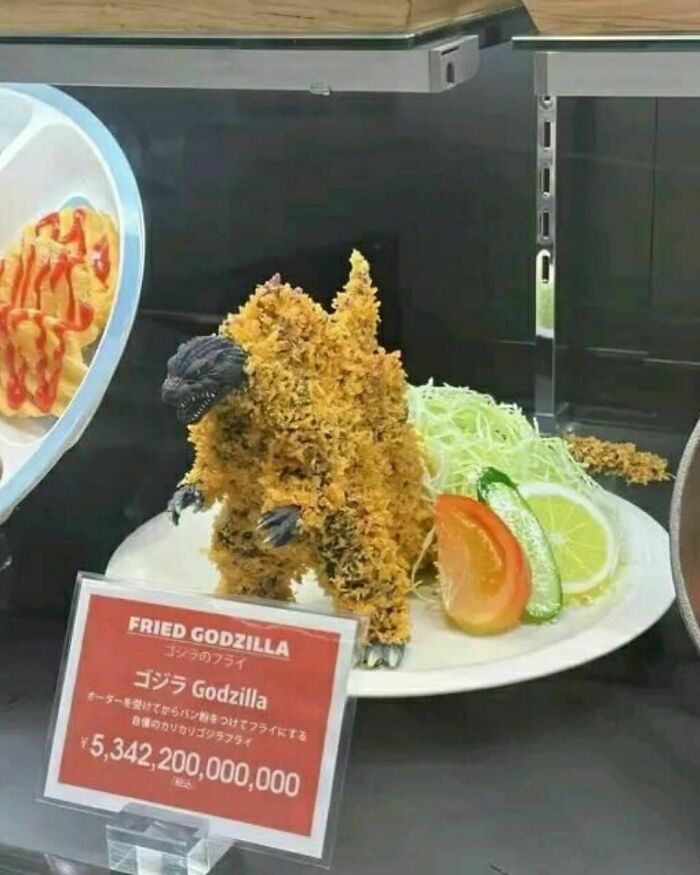 A creative "fried Godzilla" dish on display, garnished with lemon and cabbage, showcasing a humorous take on food presentation.