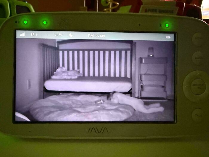 Baby monitor showing a toddler lying on a pillow in a crib, capturing a wholesome and funny dad moment.