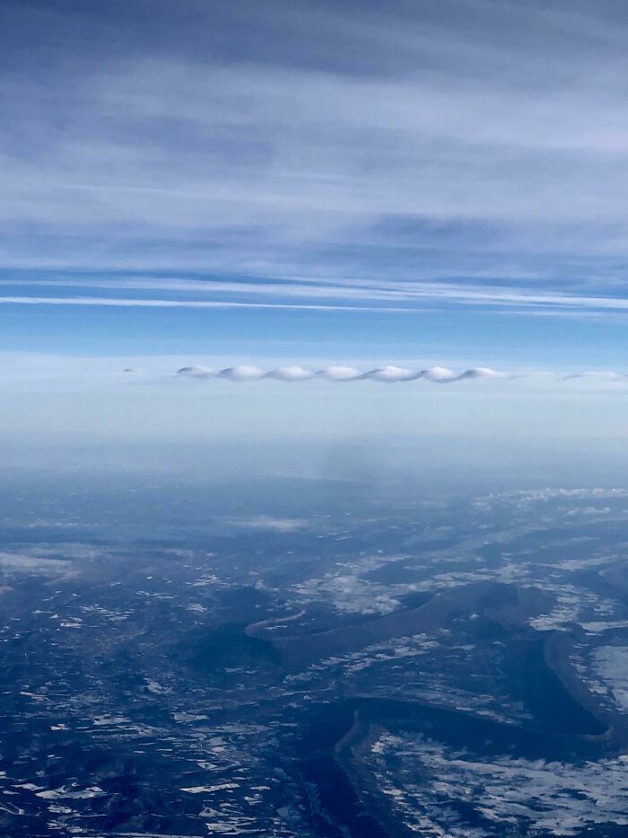 Unique cloud shapes over a vast landscape, showcasing fascinating sky formations.
