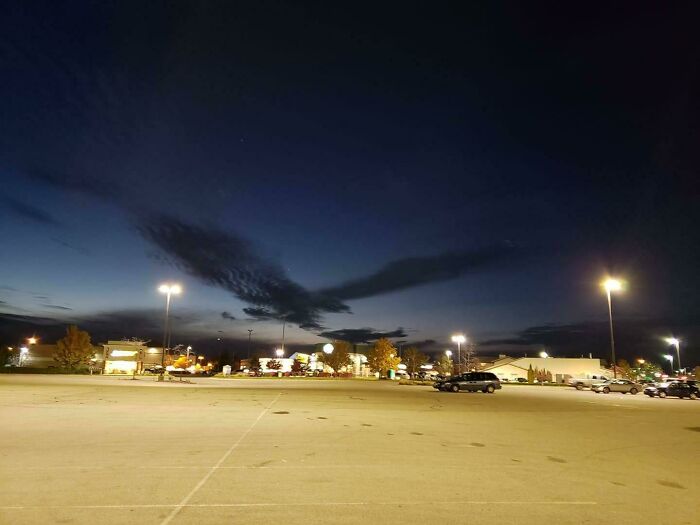 Unusual cloud shapes in the night sky over an illuminated parking lot.