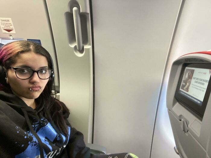 Person sitting in an airplane seat, expressing regret about spending money.