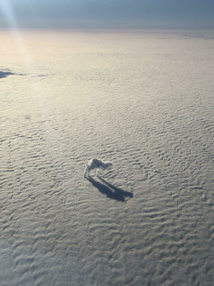 Unusual cloud shape resembling a heart casts a shadow on a vast, textured sky.