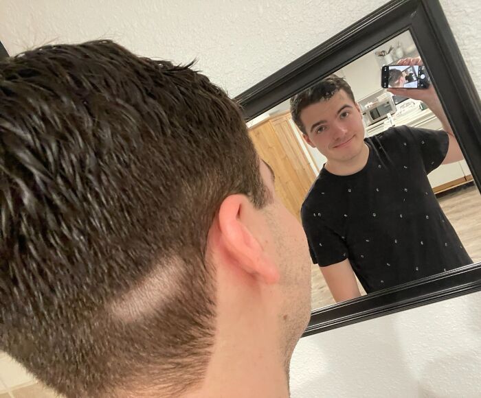 Man taking a selfie in the mirror, showing uneven haircut as a hair-cutting-dyeing-fails example.