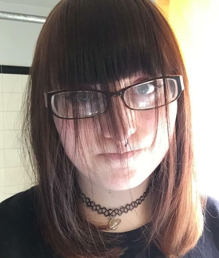 Woman wearing glasses with uneven bangs covering her eyes; example of hair-cutting-dyeing-fails.