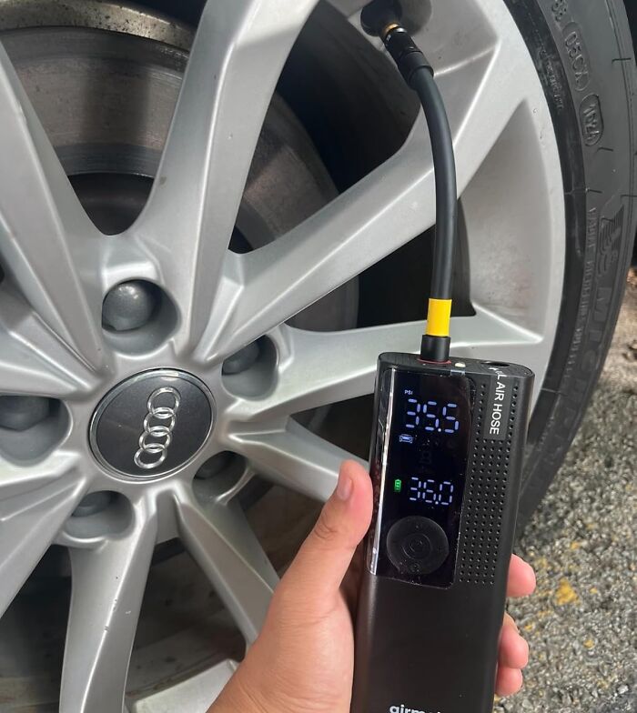 Hand holding a digital tire inflator pumping air into an Audi car wheel, one of the most-wished-for Amazon finds.
