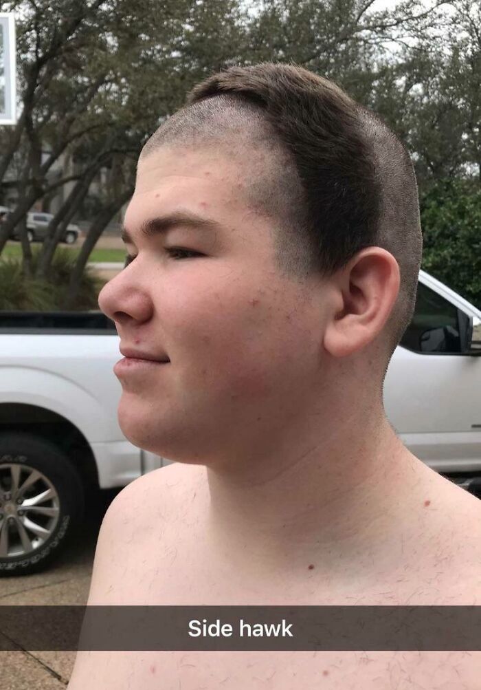 Teen boy with uneven haircut in yard, a classic hair-cutting fail, dubbed "side hawk," next to a truck.