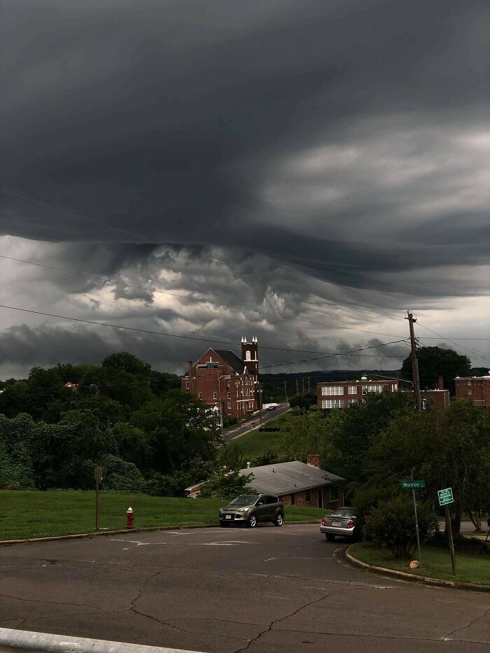 Breathtaking cloud shapes hover over a small town street, creating a dramatic sky scene.