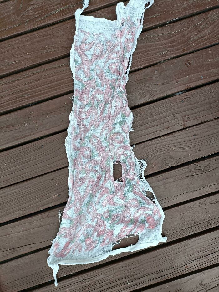 Torn and worn-out red patterned dress on wooden deck, evoking infuriating wives or girlfriends theme.