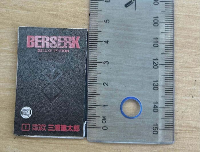 Tiny "Berserk" deluxe book next to a ruler, showing a small purchase regret after months of saving.