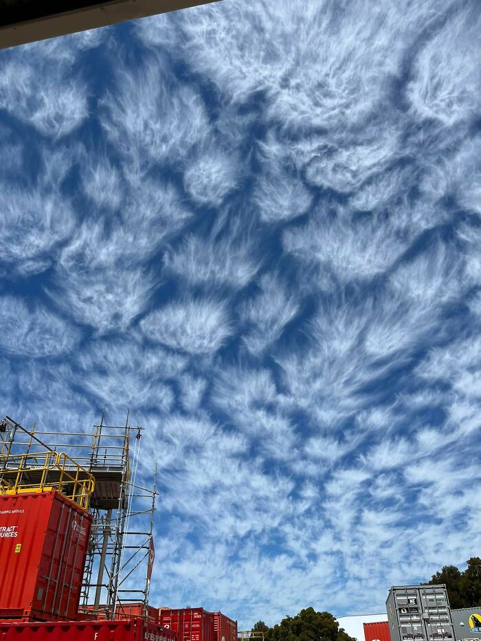 Fascinating cloud shapes above construction site, resembling intricate wisps in the sky.