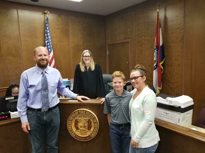 Happy family in a courtroom celebrating a successful adoption with a judge, embodying wholesome adoption stories.