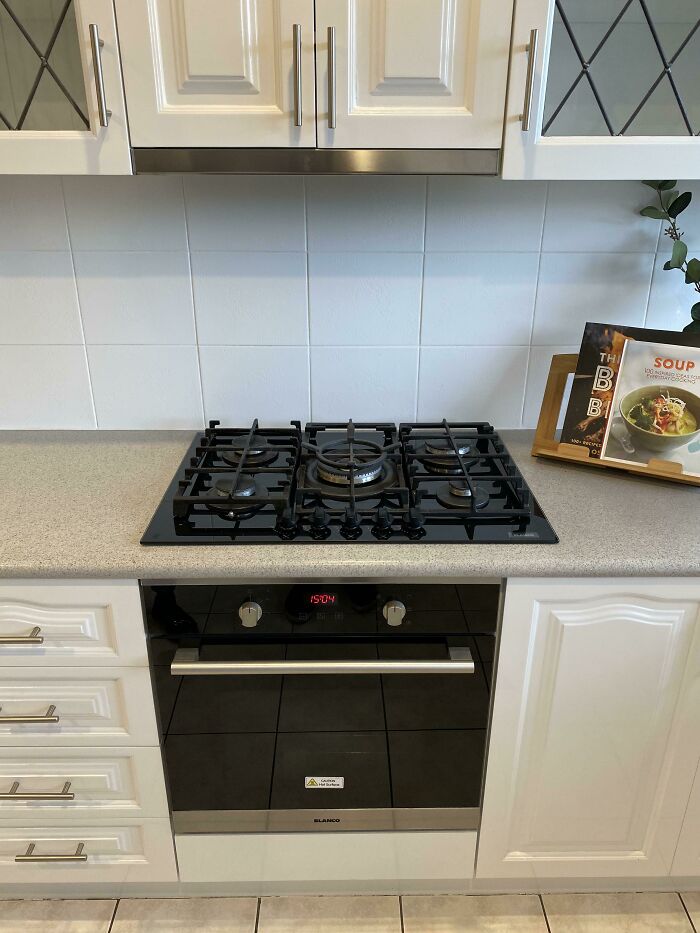 Kitchen with gas stove under non-functional cabinet, showcasing a home improvement fail.