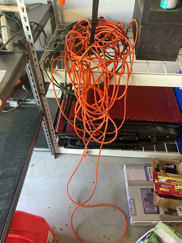 Tangled orange extension cords hanging in a garage, illustrating infuriating organization challenges.