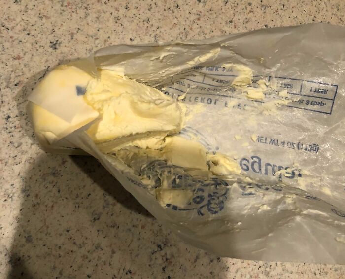 Partially unwrapped butter with uneven cuts on a kitchen counter, highlighting everyday frustrations in relationships.