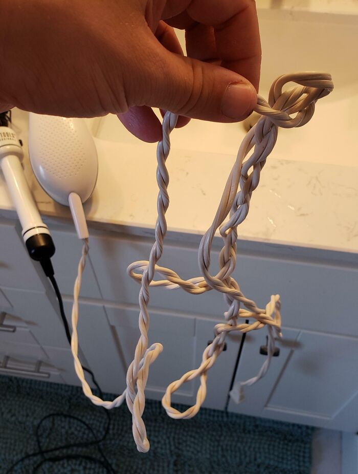 Tangled hairdryer cord held by a hand, depicting a messy situation often caused by wives or girlfriends.