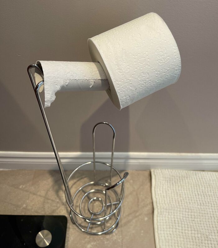 Toilet paper roll placed incorrectly on a holder, potentially causing frustration for those using it.