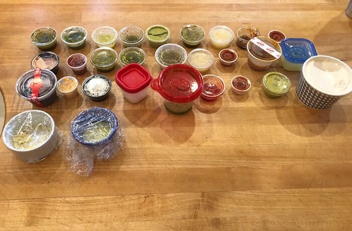 Various condiment containers organized on a wooden table, related to infuriating actions by wives or girlfriends.