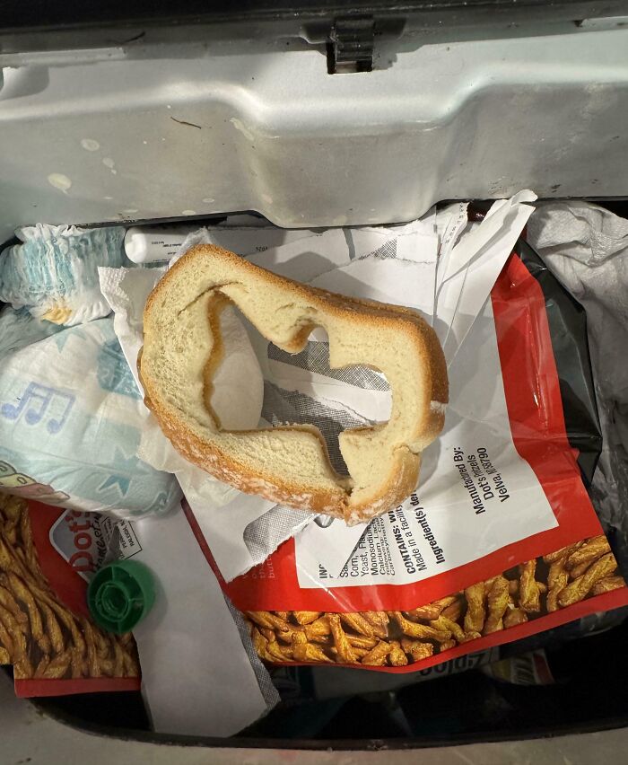 A slice of bread with the center removed, resting atop various discarded items in a trash bin, symbolizing infuriating behavior.