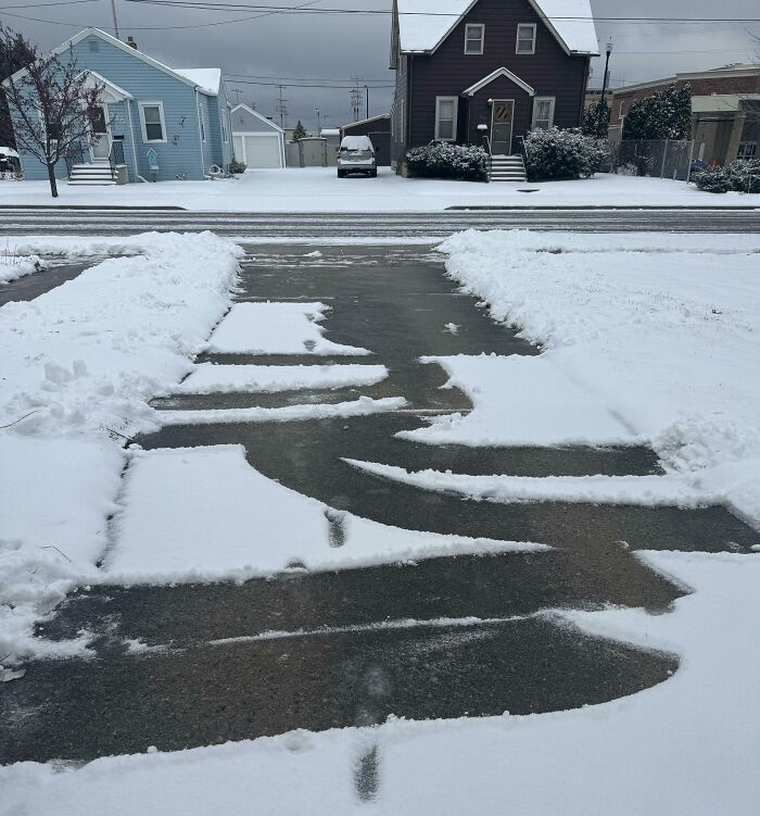 Unevenly shoveled snowy driveway with patches of snow, in front of suburban homes, illustrating infuriating situations.
