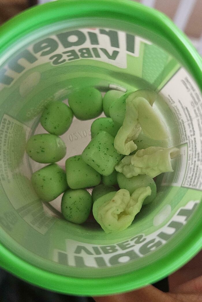 Container of green mints with garlic cloves mixed in, creating an unexpected surprise.