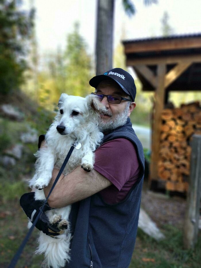 Man joyfully hugging his newly adopted dog outdoors.