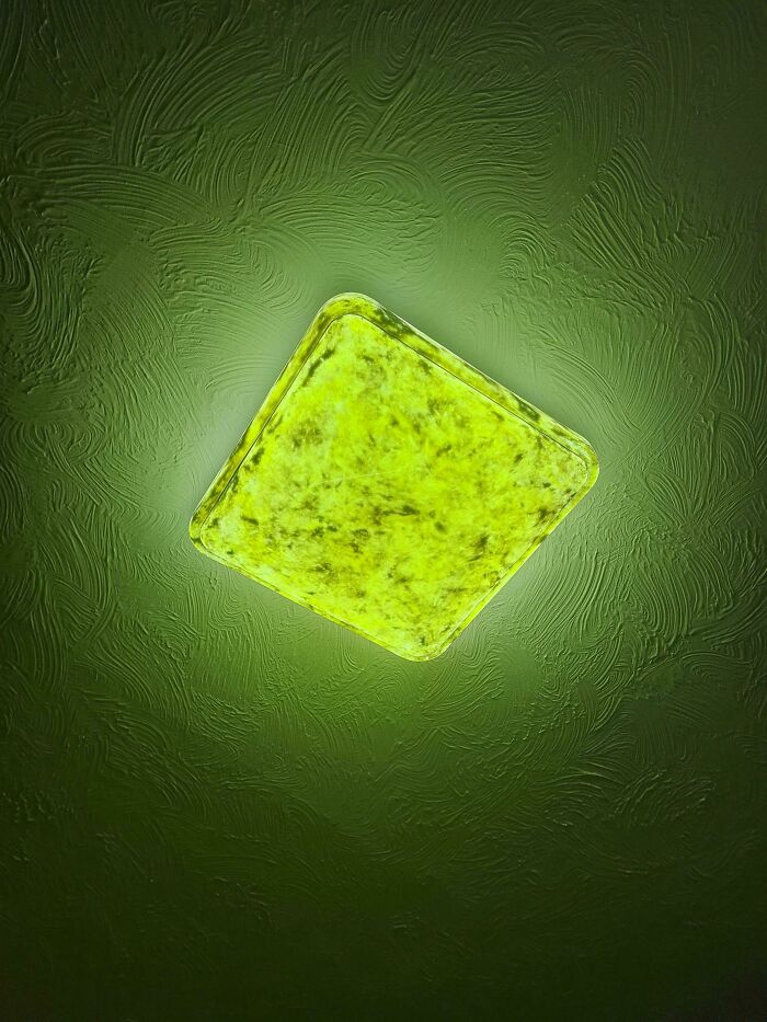 Square green ceiling light highlighting a textured surface, showing a home improvement fail.