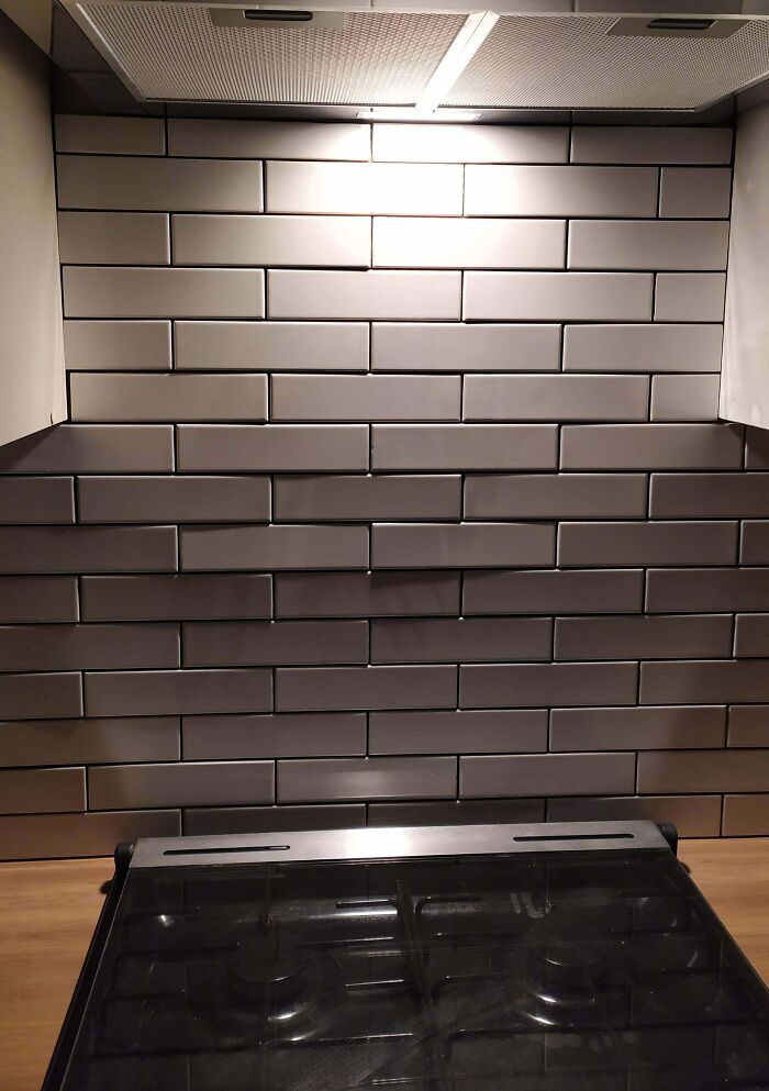 Poorly aligned kitchen backsplash tiles above a stove, highlighting home improvement fails.