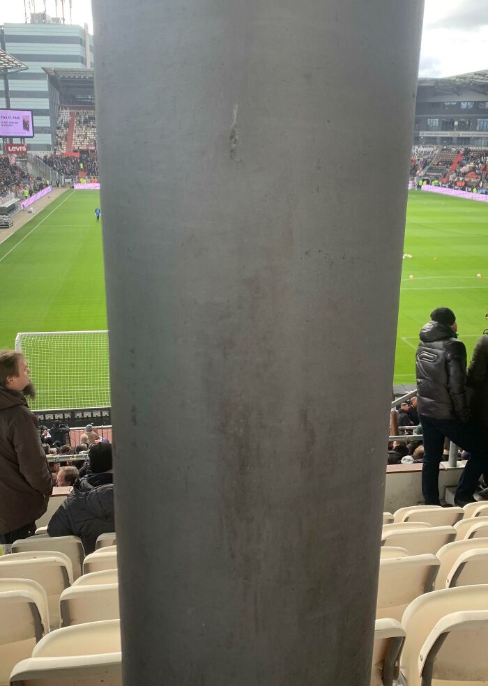 Football match obstructed by a large pillar, highlighting buyer's regret after spending months saving for tickets.