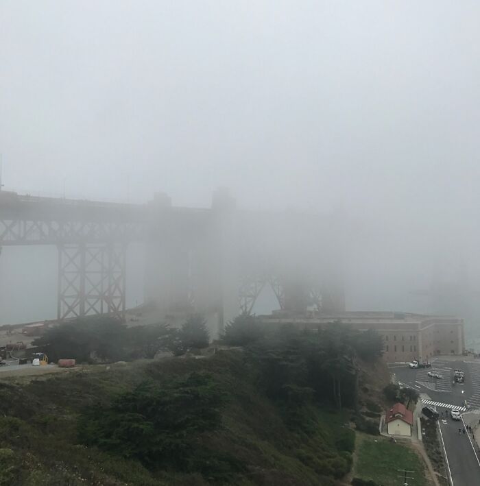 Fog obscures the view of a large bridge, symbolizing regretful spending decisions.