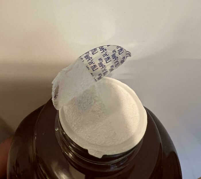 Partially peeled bottle seal, irritating packaging detail, mildly infuriating experience.