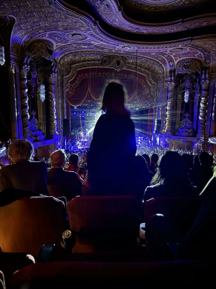 Person standing and blocking the view of a theater stage, illustrating people being jerks.