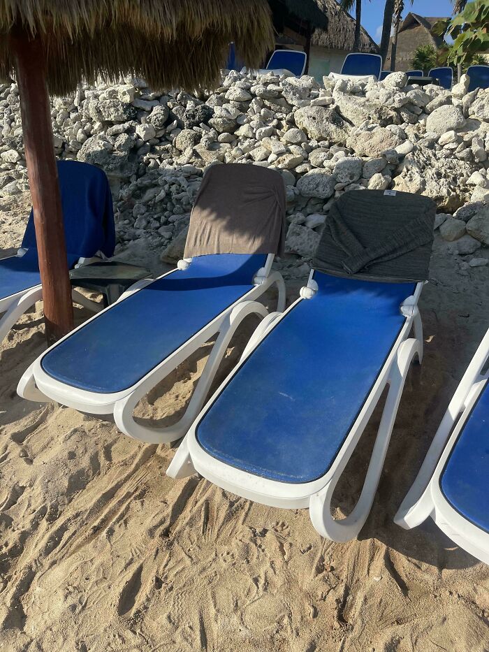 Beach chairs reserved with towels, no people; example of people being jerks at the beach.