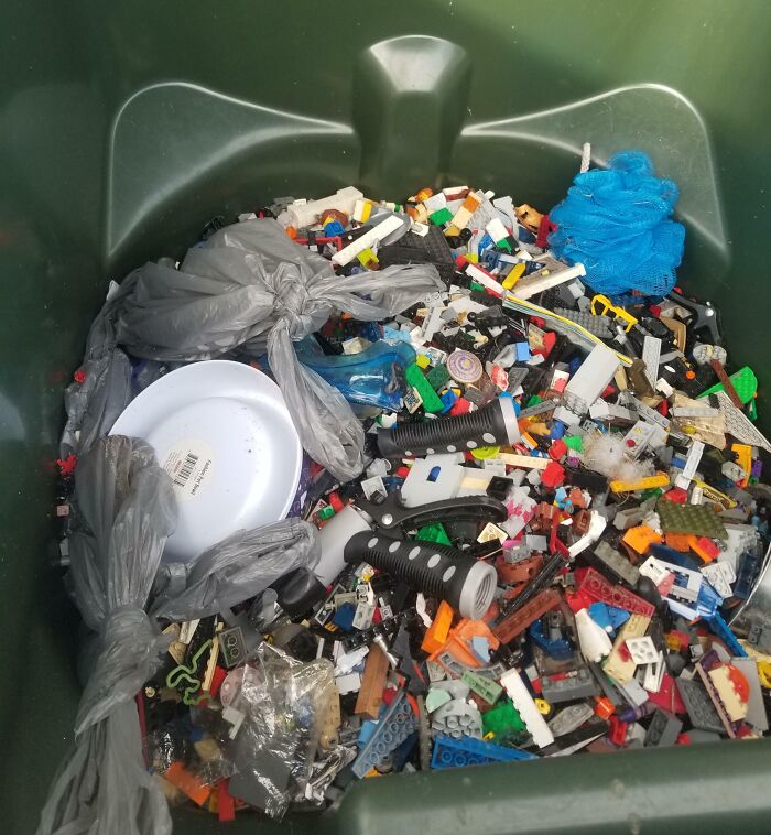 Trash bin filled with LEGO bricks, household items, and plastic bags, illustrating the messy habits of boyfriends and husbands.