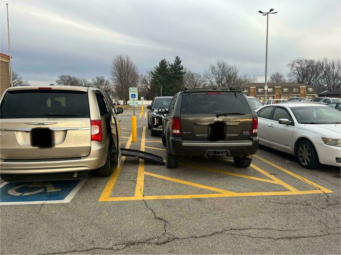 Cars improperly parked in a handicapped zone, blocking access.