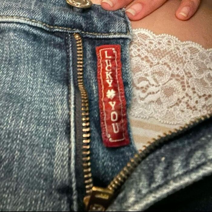 '90s moment: Unzipped denim with "Lucky You" tag, revealing lace beneath.