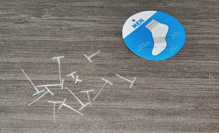 Plastic tags on a wooden surface next to a sock label, an irritating thing.
