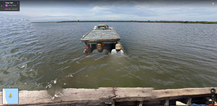 Two people sitting in water inside a boat on a lake, a funny scene captured on Google Street View.