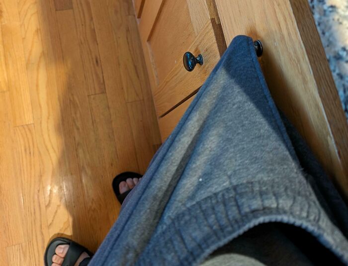Sweatpants caught on a cabinet k**b in a kitchen, illustrating mildly infuriating things.
