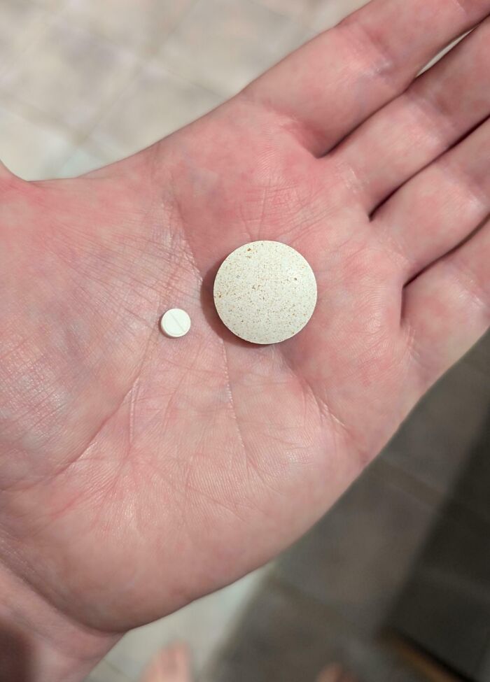Two differently sized pills in a palm, highlighting irritating discrepancies in size.