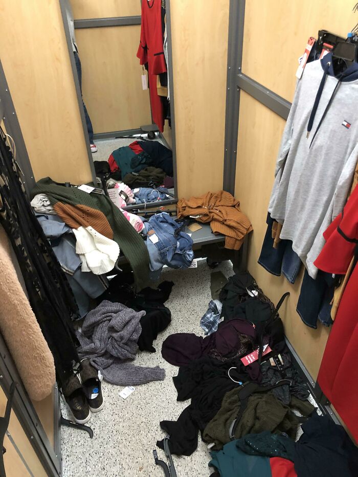 Messy fitting room with clothes scattered everywhere, showcasing people being jerks.
