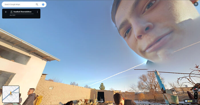 A person's face unexpectedly appears large in the sky on a Google Street View scene, creating a funny and weird effect.