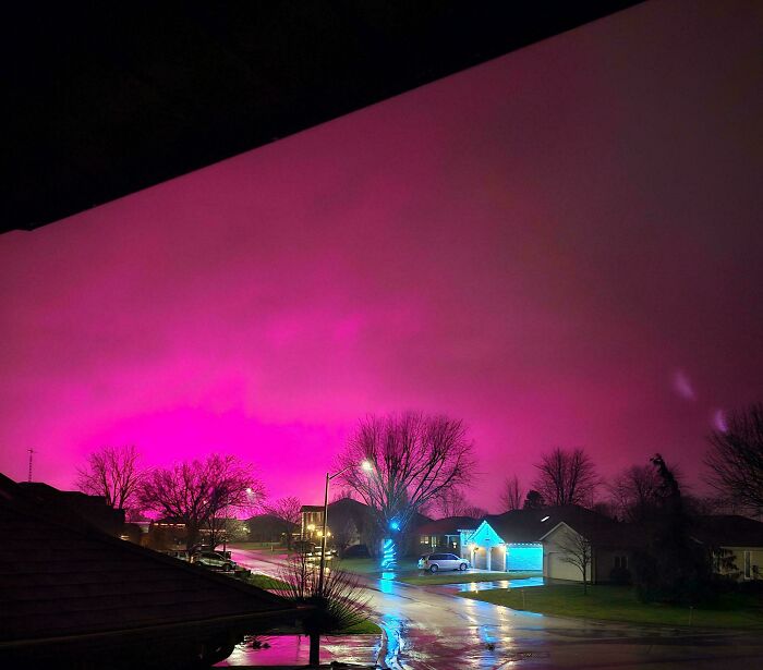 Vibrant pink sky over a suburban street at dusk, illustrating an interesting not photoshopped phenomenon.